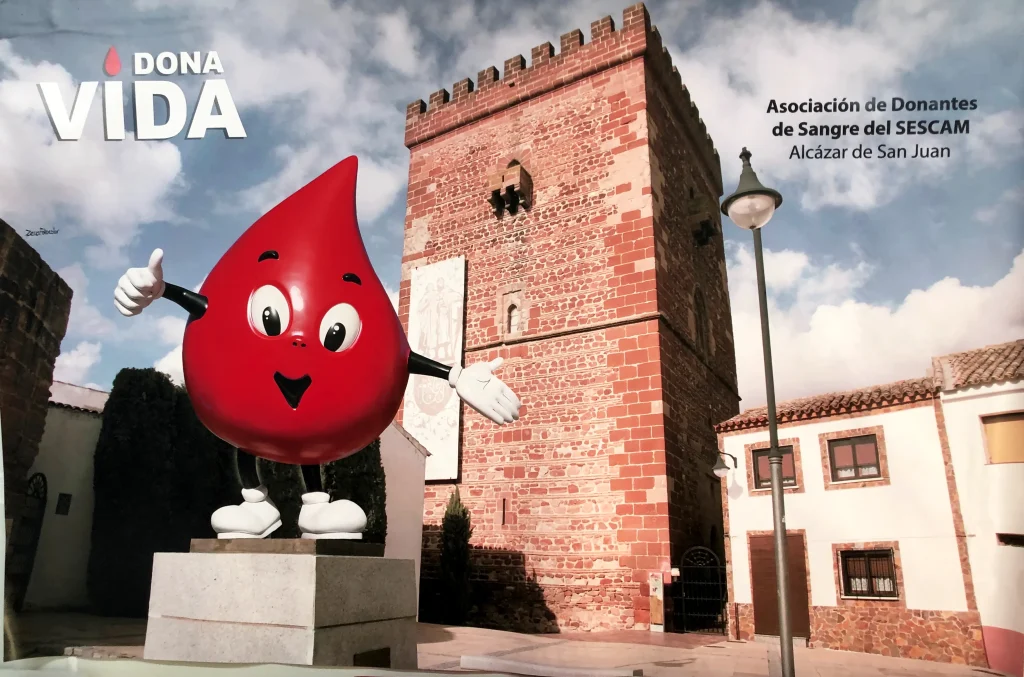 Cartel publicitario de la asociación de donantes de sangre de alcázar de san juan mostrando a gotito en el torreón de la ciudad